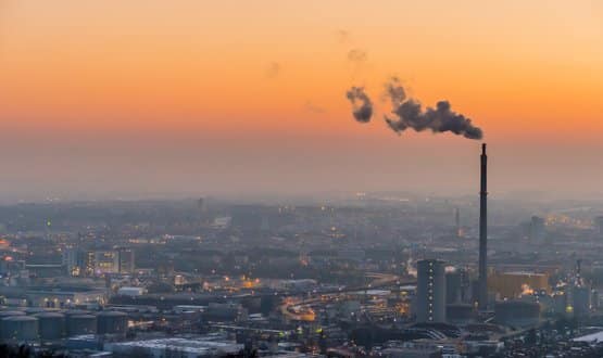 A smoke stack billows smoke over a city